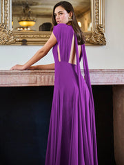Woman in a purple evening gown standing in an elegant interior setting.