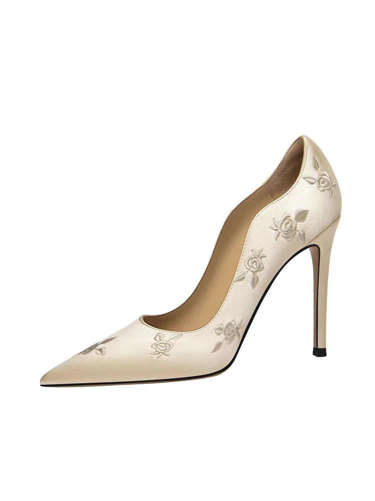 Beige high-heeled shoe with floral embroidery on a white background