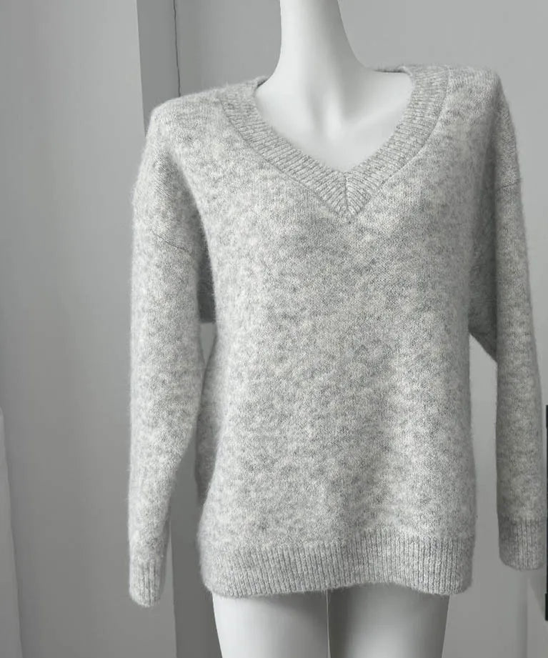 Gray sweater on a mannequin with a framed quote 'EVERYTHING WILL BE FINE' in the background.