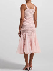 Pink textured dress worn by a person on a light gray background