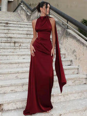 Woman in a burgundy evening gown standing on stone steps.