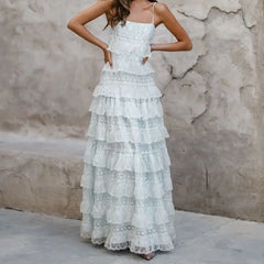 Woman wearing a white lace dress against a textured wall.