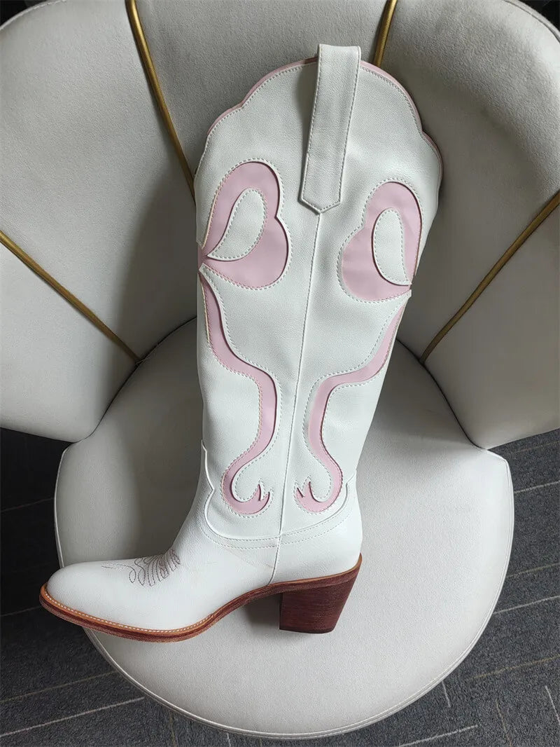 White cowboy boot with pink stitching on a white chair.