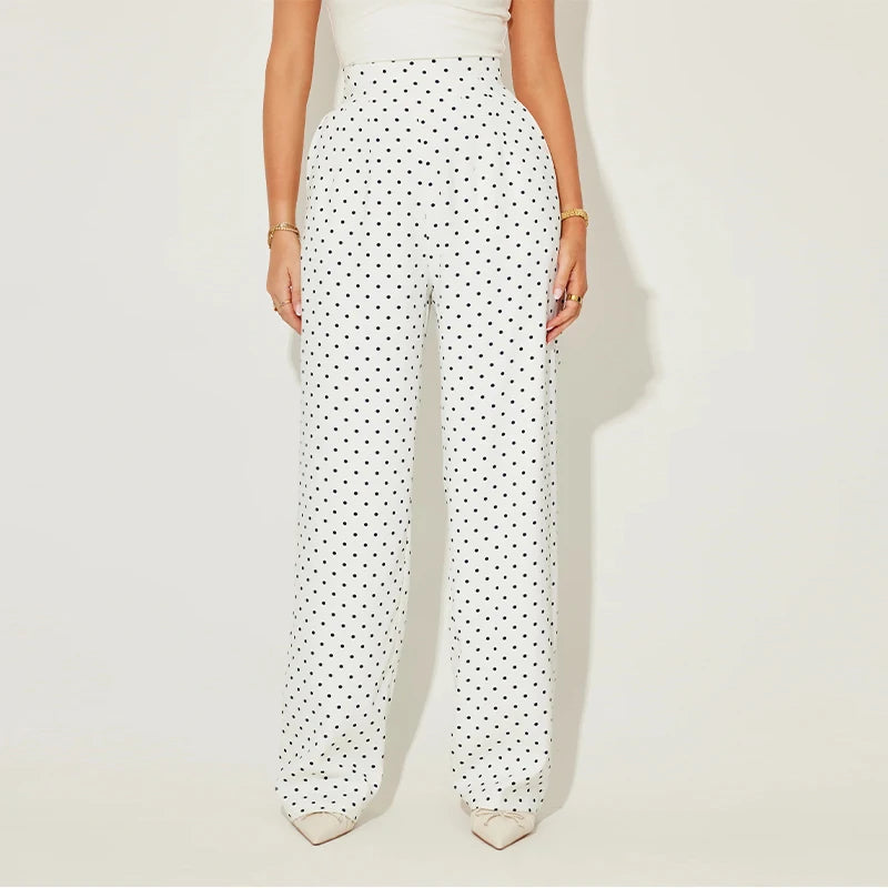 White pants with black polka dots worn by a person on a light beige background