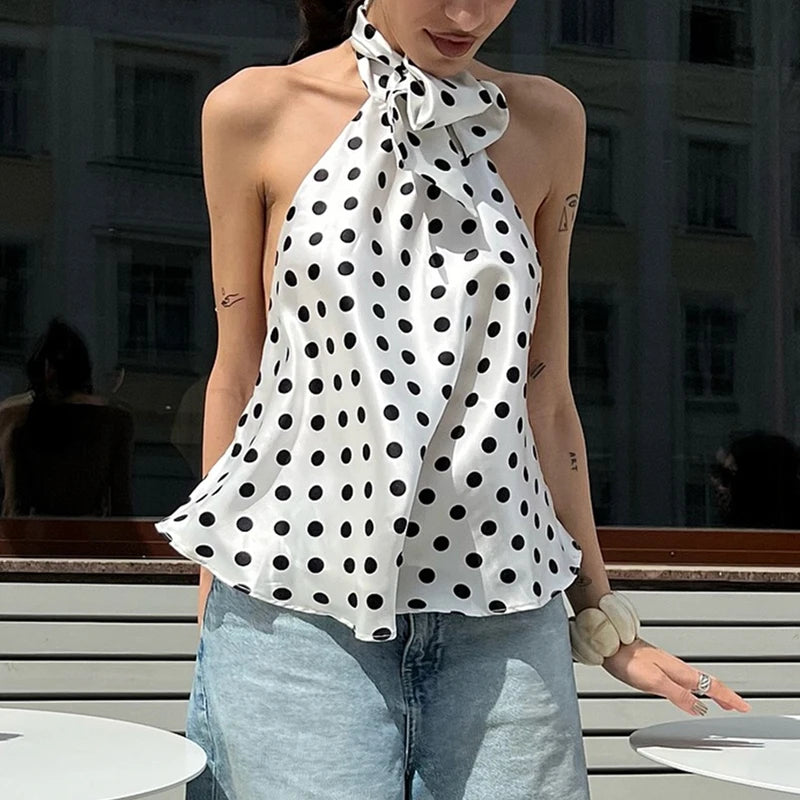 Woman wearing a polka dot halter top and jeans outdoors.