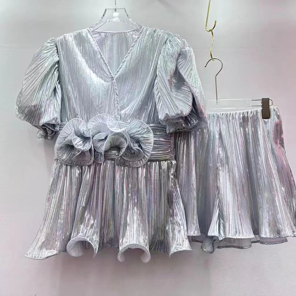 Silver metallic dress with puff sleeves and a matching skirt on hangers against a white background