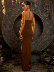Woman in a brown dress standing in front of an intricate circular design with plants around.
