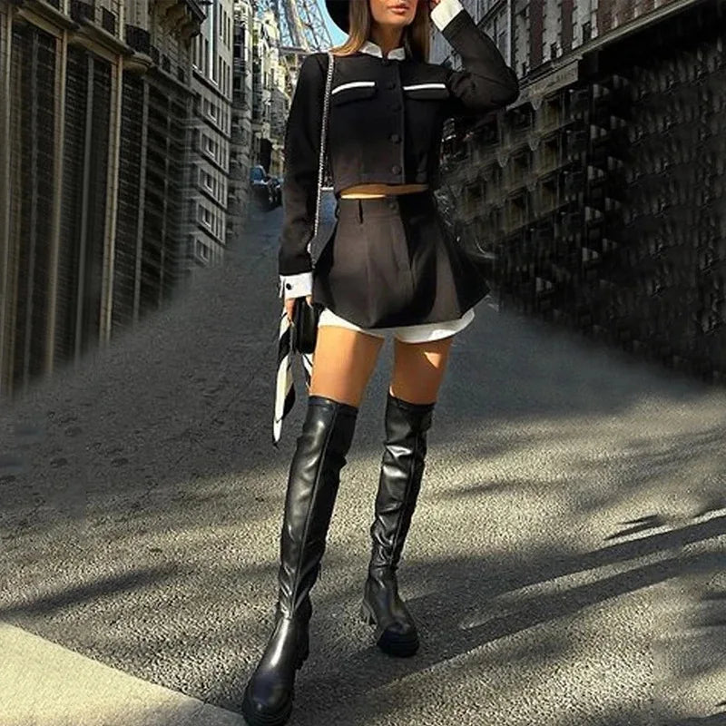 Woman in black outfit with knee-high boots on a city street
