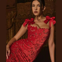 Woman wearing a red lace dress with large bows on a dark background