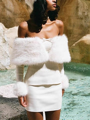 Woman wearing a white dress with fur accents by a poolside.