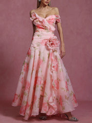 Woman wearing a pink floral off-shoulder gown against a pink background