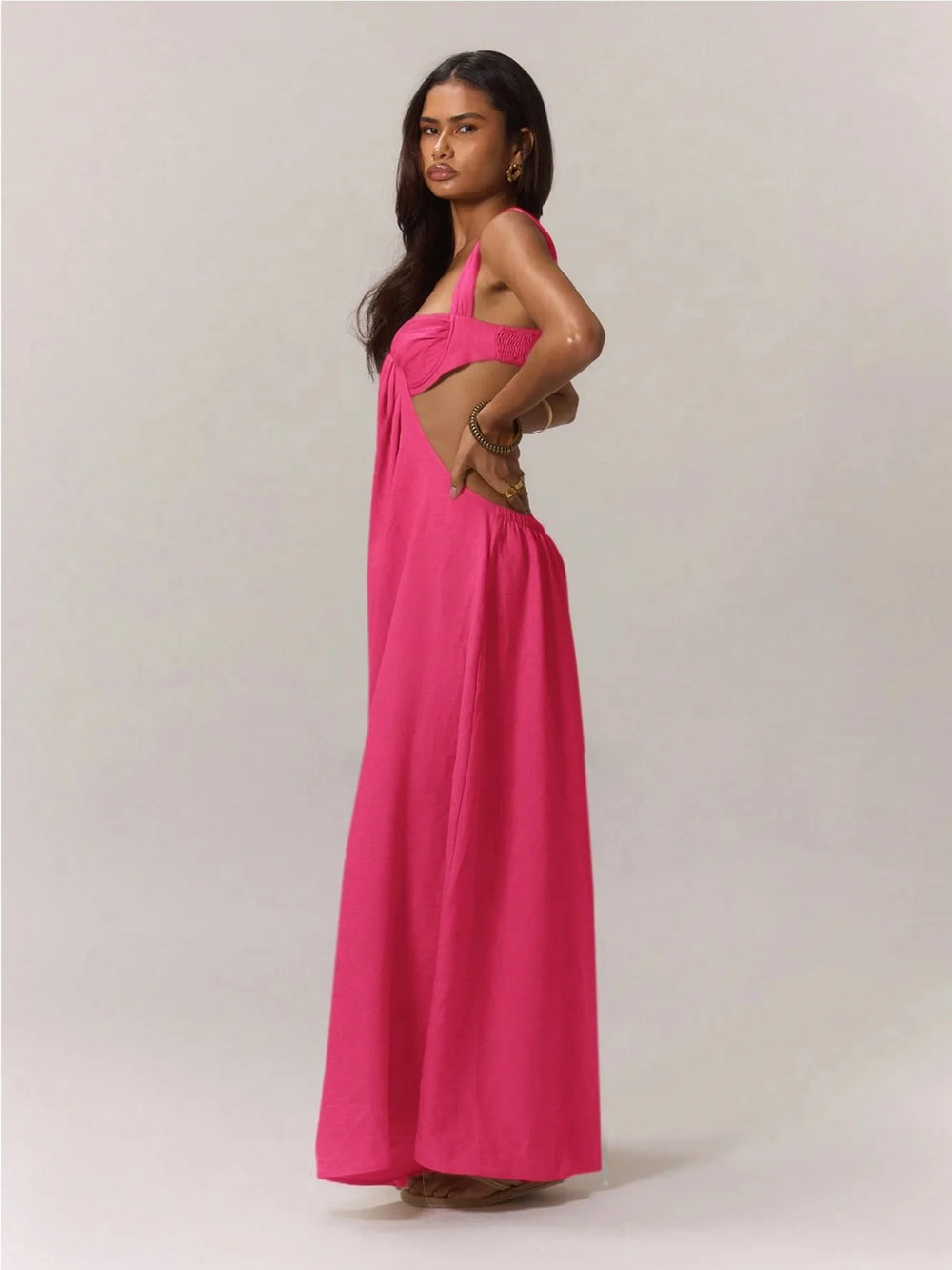 Woman wearing a pink jumpsuit with a cut-out design on a plain background