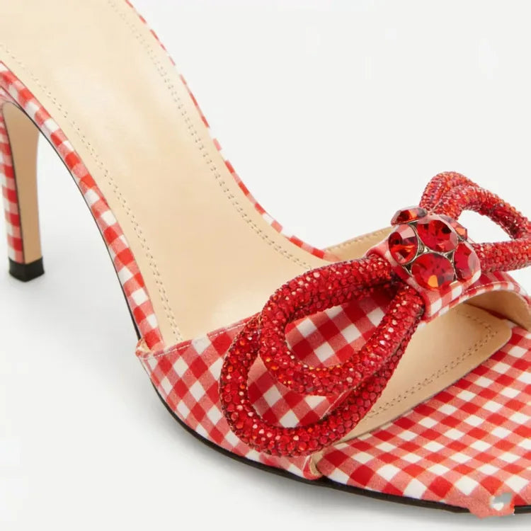 Red and white checkered high-heeled shoe with decorative bow on a light background