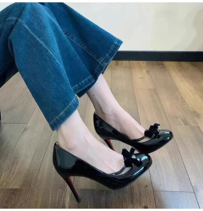 Model wearing black patent leather bow pumps dress