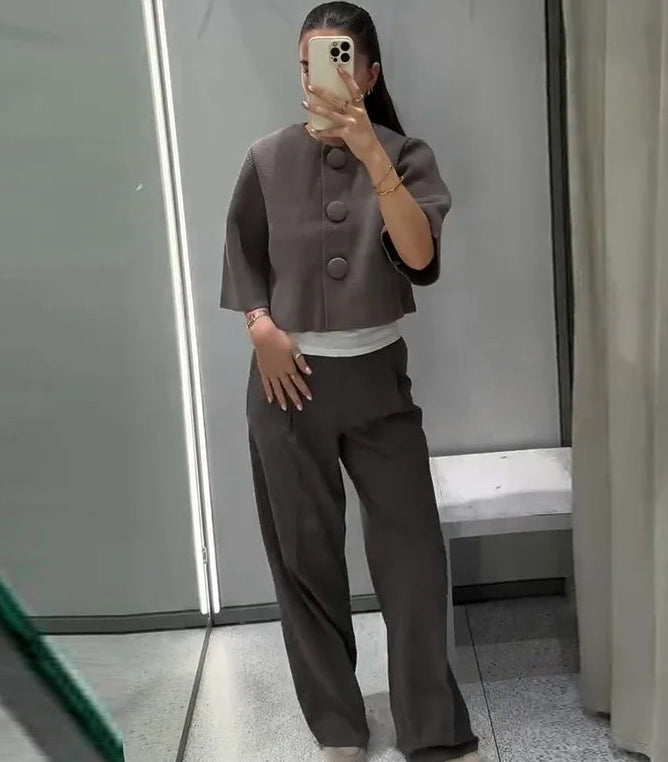 Person wearing a brown outfit taking a mirror selfie in a bathroom.