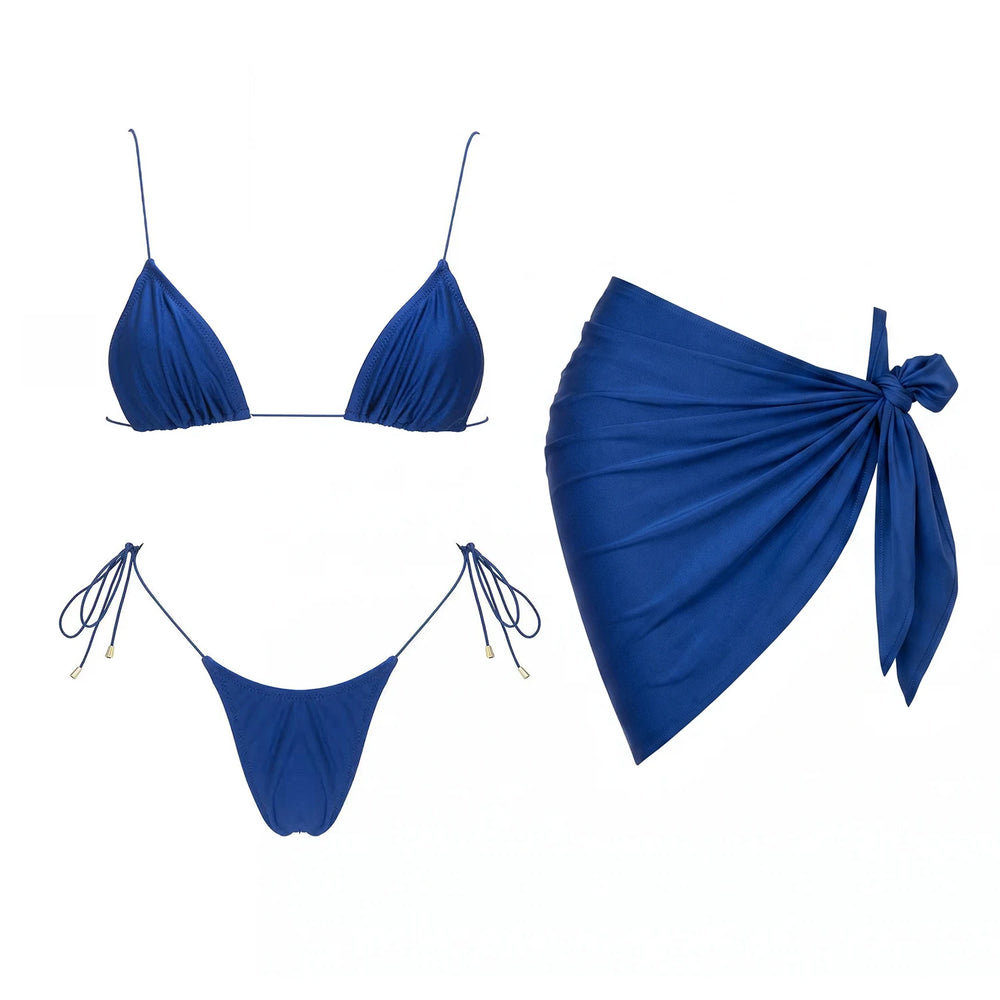 Blue triangle bikini top and bottoms next to a blue wrap skirt.