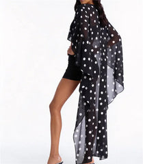 Side view of black polka dot sheer cape top with high low hem