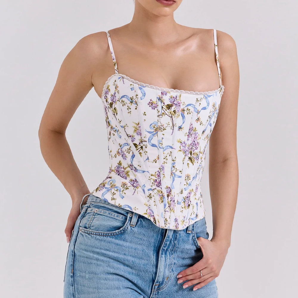 Woman wearing a floral camisole top and jeans on a plain background