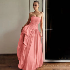 Woman wearing a pink strapless gown standing indoors.