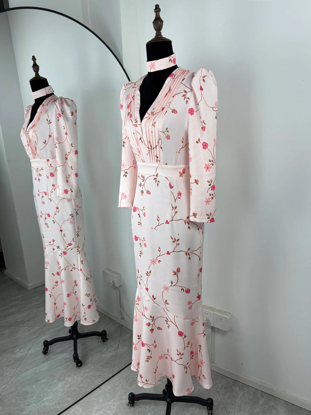 Floral-patterned dress on a mannequin against a white wall.
