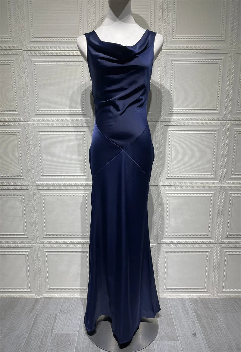 Navy blue evening gown on a mannequin against a white paneled wall.