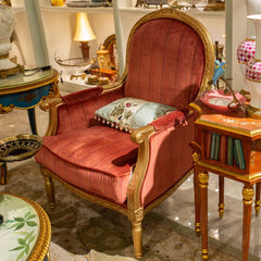 Decorative chair with gold frame and red cushions in a room with ornate furniture.