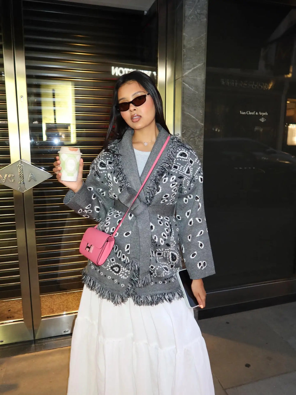 Woman holding a coffee cup in front of a building entrance