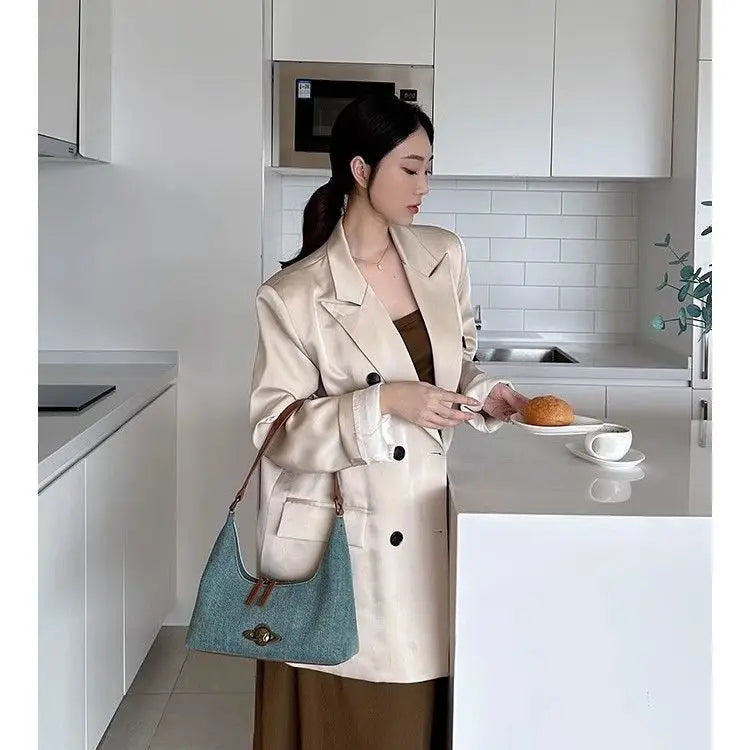 Woman in a beige coat holding a plate with a pastry in a kitchen.