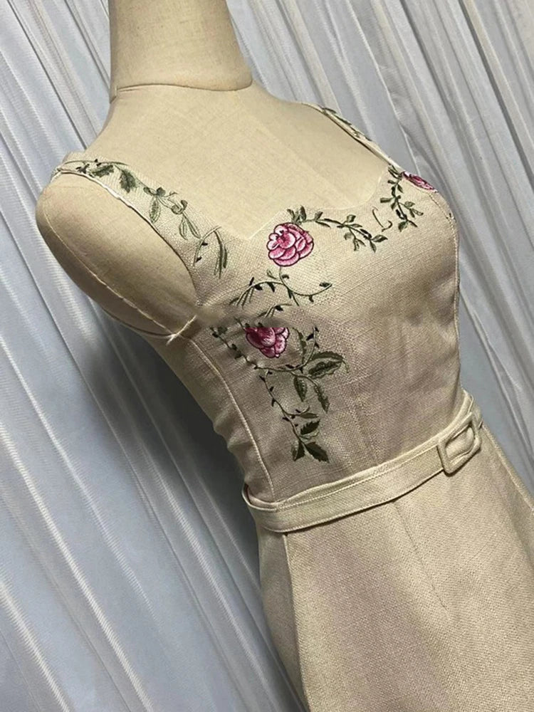 Beige dress with floral embroidery on a mannequin against a white curtain background