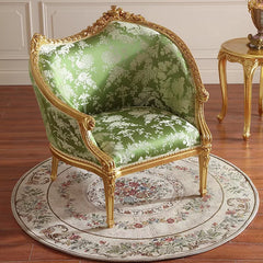 Decorative armchair with gold frame and green floral pattern on a wooden floor.