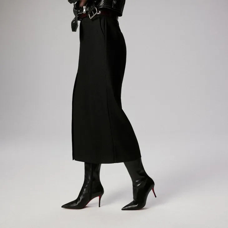 Person wearing black high-waisted pants and black boots on a gray background