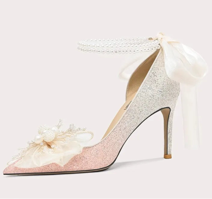High-heeled shoe with decorative bow and floral details on a white background