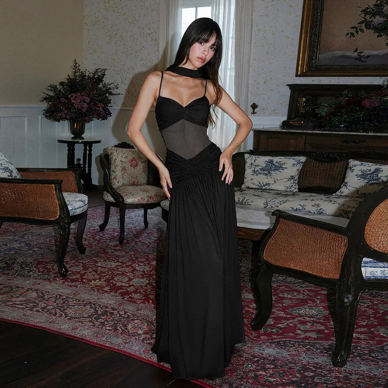 Woman in a black dress standing in an elegant room with floral-patterned furniture.