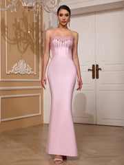 Woman wearing a pink strapless gown with beaded top in an elegant interior setting.
