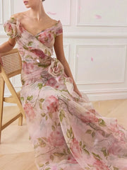 Woman wearing a floral dress in a room with a wooden chair and white walls.