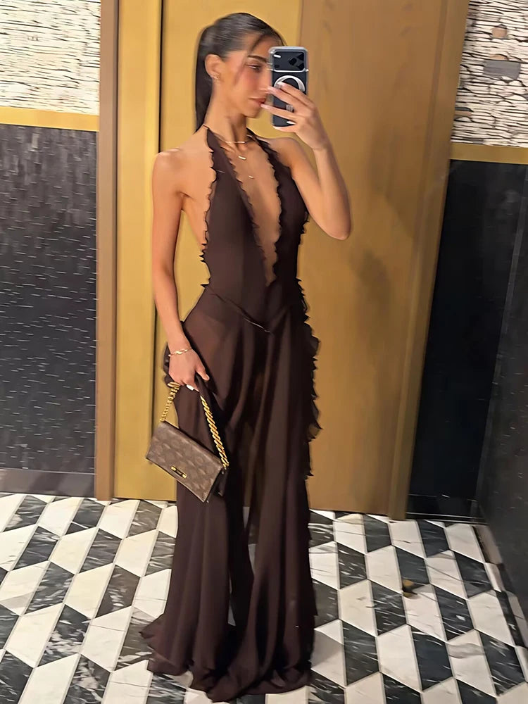 Woman taking a mirror selfie wearing a brown dress with a patterned floor and wall in the background.