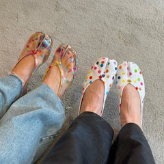 Person wearing colorful polka dot split-toe flats and jeans