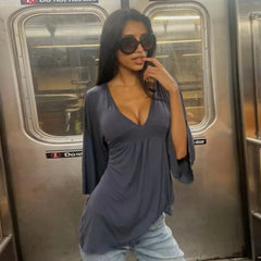 Woman in a gray top and jeans standing inside a subway car.