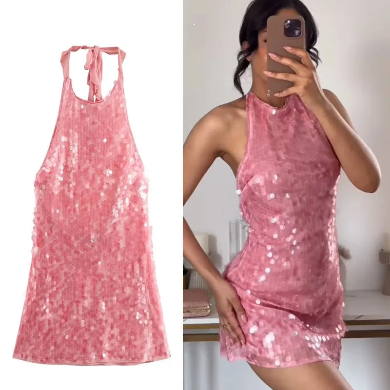 Pink sequin dress shown on a white background and worn by a person indoors.