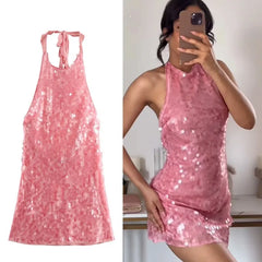 Pink sequin dress shown on a white background and worn by a person indoors.