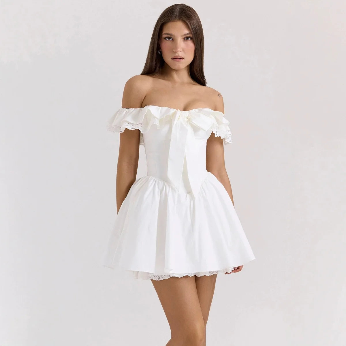Woman wearing a white off-shoulder dress on a plain background