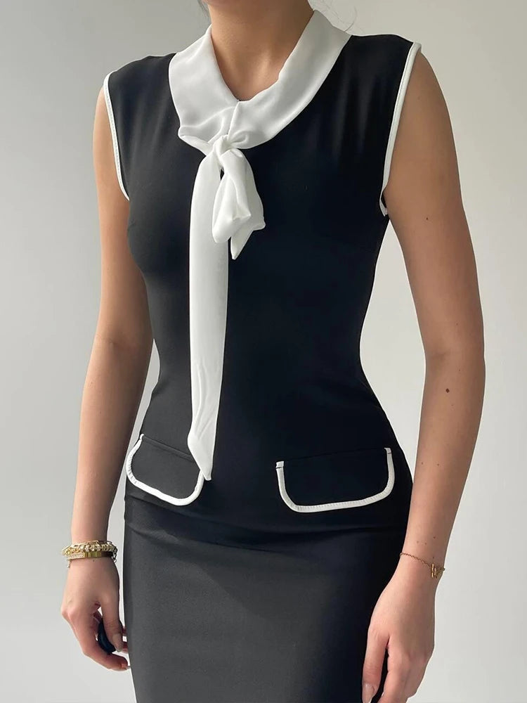 Black sleeveless top with white collar and trim worn by a person on a plain background