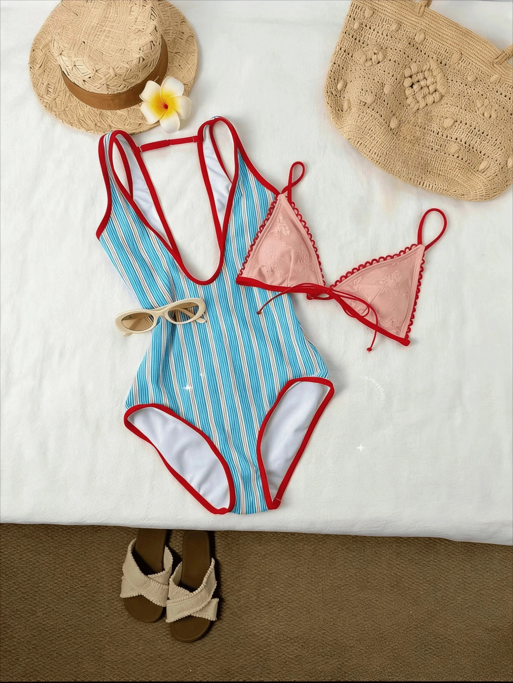 Blue and white striped one-piece swimsuit with red trim, pink lace bikini top, straw hats, woven bag, sunglasses, and sandals