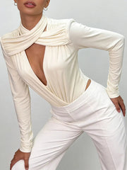 Person wearing an apricot long-sleeve top and white pants on a grey background