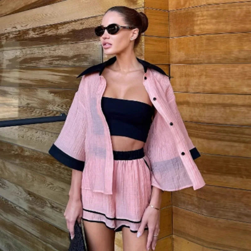 Woman wearing a pink outfit with black accents against a wooden wall.