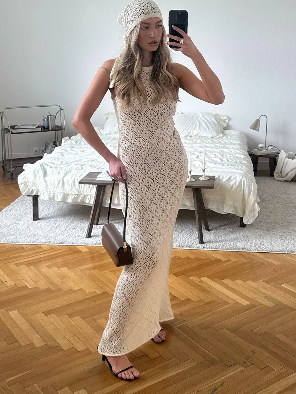 Woman taking a mirror selfie in a patterned dress in a bedroom.