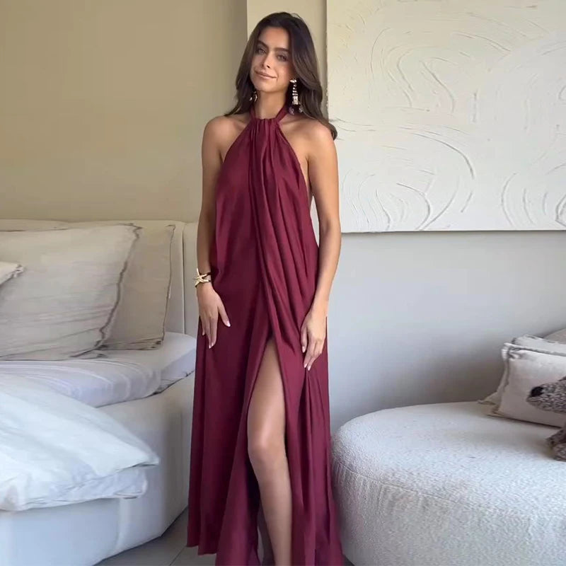Woman in a burgundy halter neck dress standing in a modern living room.