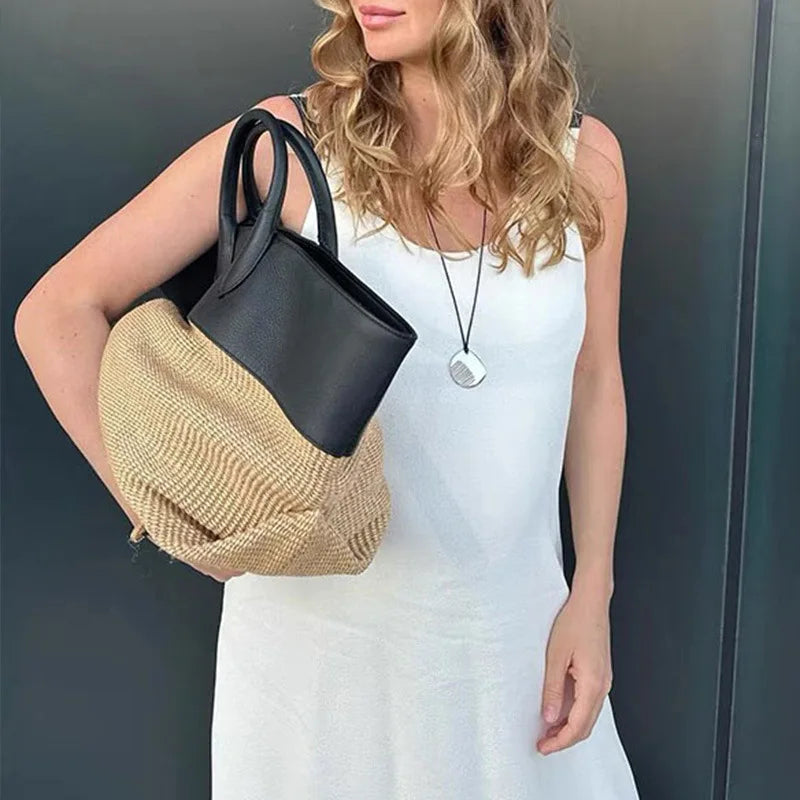 Woman holding a colorblock tote bag with straw and leather