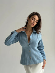 Woman wearing a blue denim shirt against a plain background