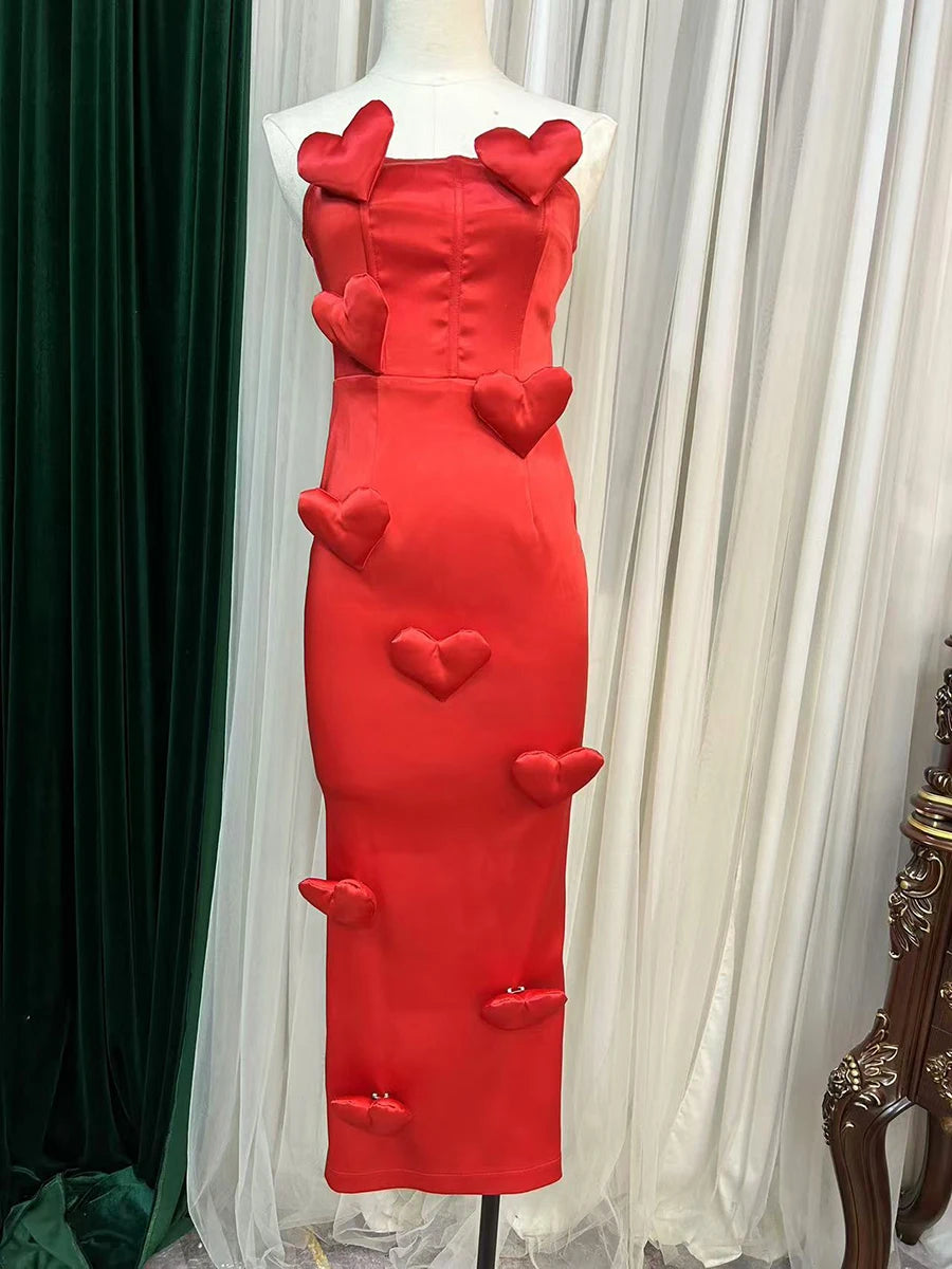Red dress with heart designs on a mannequin against a white curtain background